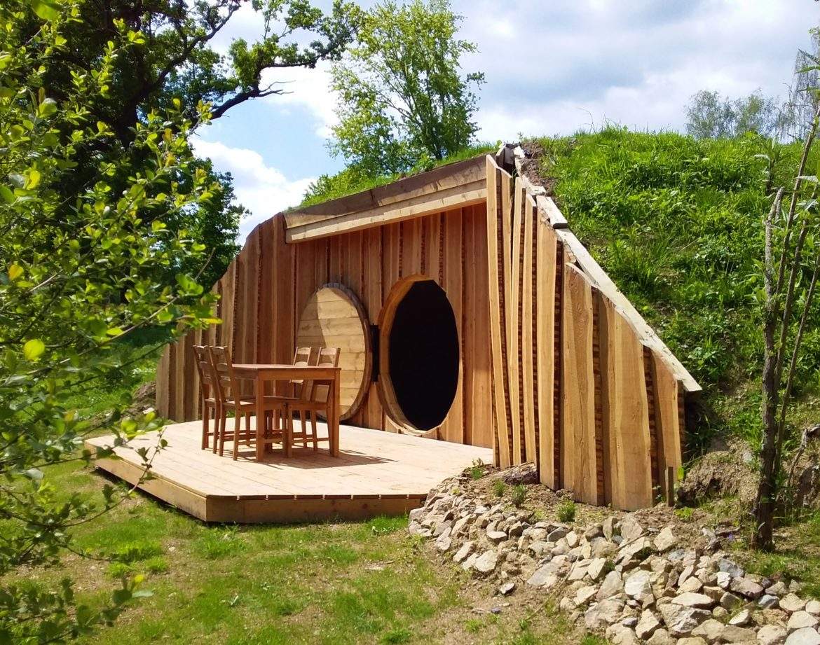 Hébergement insolite en Auvergne : cabane en bois avec terrasse et vue verdoyante.