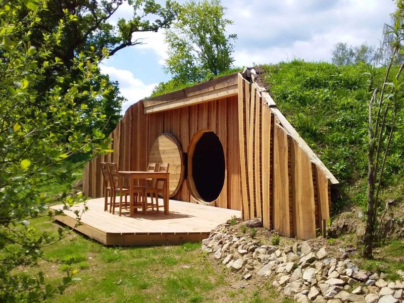 Hébergement insolite en Auvergne : cabane en bois avec terrasse et vue verdoyante.