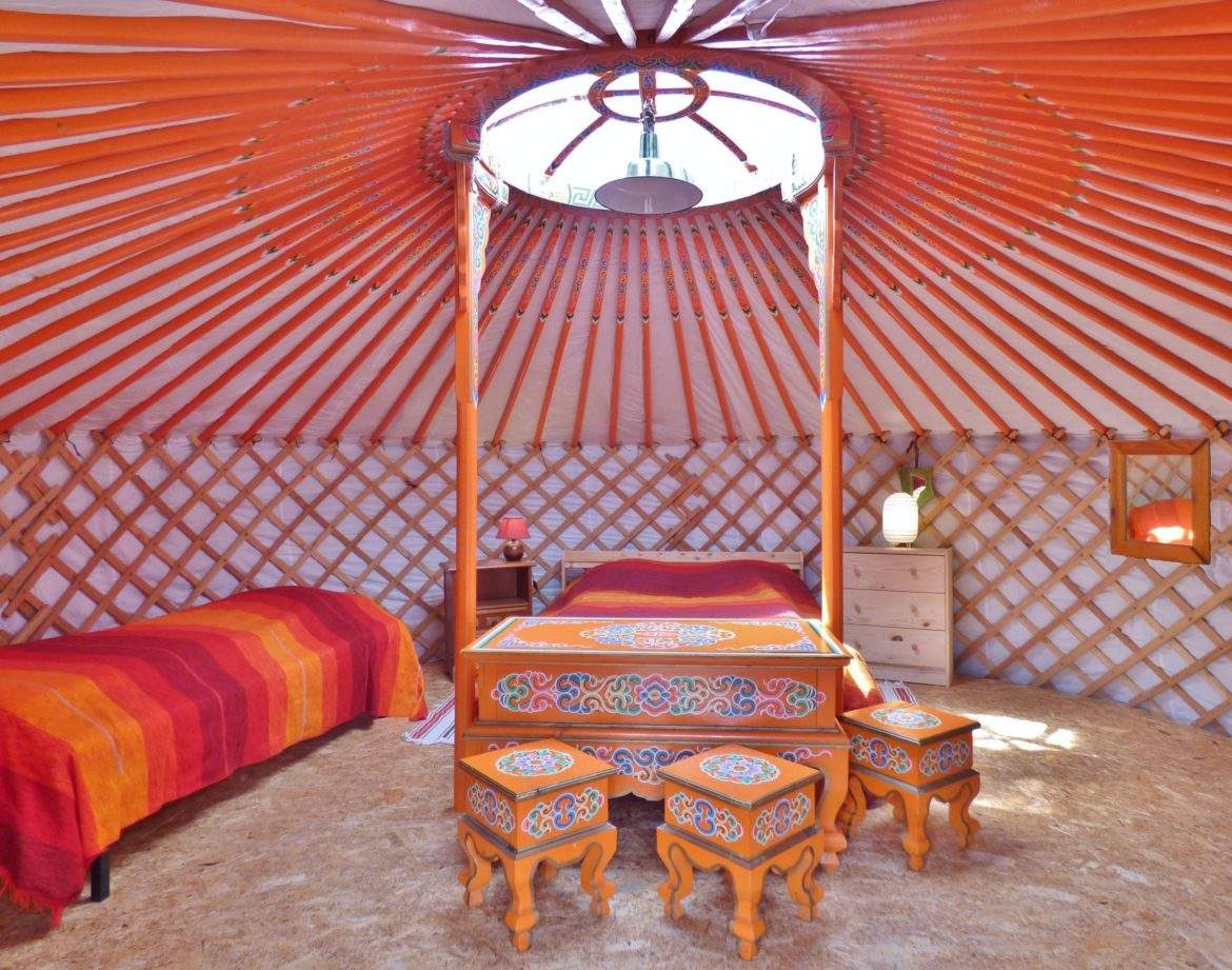 Yourte colorée en Auvergne, avec un lit douillet et des meubles décoratifs.