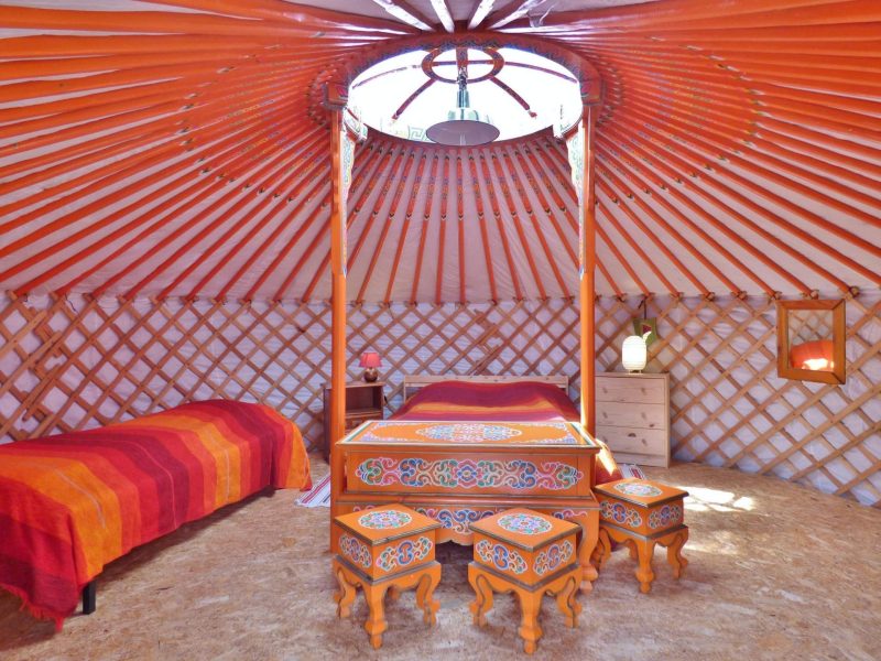 Yourte colorée en Auvergne, avec un lit douillet et des meubles décoratifs.
