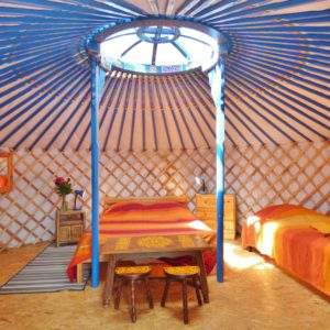 Yourte colorée en Auvergne, avec un lit central et des décorations chaleureuses.