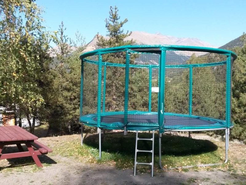 Trampoline entouré de verdure près dun hébergement en pleine nature.