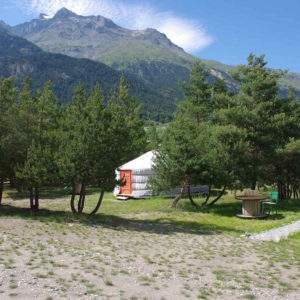 Yourtes colorées entourées de verdure, avec des montagnes en arrière-plan en Auvergne-Rhône-Alpes.