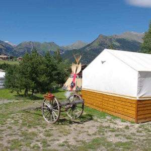 Tipi et yourte au cœur des montagnes, entourés de verdure et dun ciel bleu.