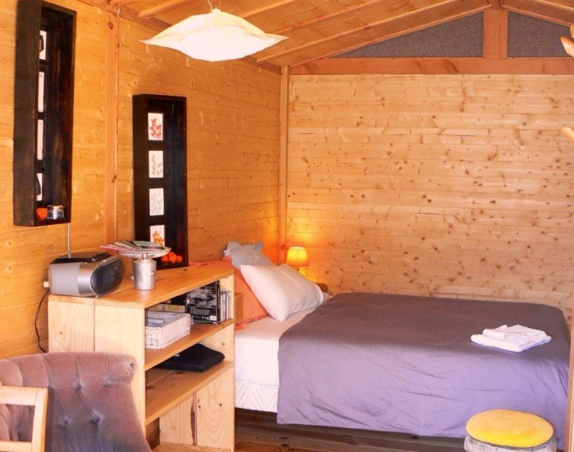 Cabane en bois cosy avec lit douillet et décoration chaleureuse. Parfait pour un séjour unique.
