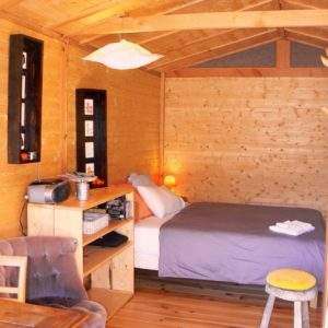 Cabane en bois cosy avec lit douillet et décoration chaleureuse. Parfait pour un séjour unique.