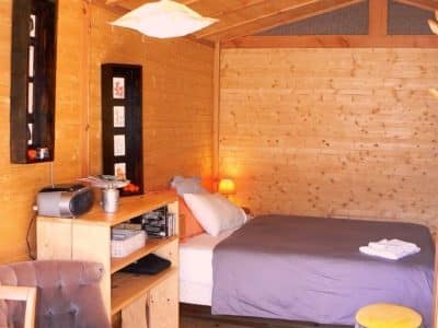 Cabane en bois cosy avec lit douillet et décoration chaleureuse. Parfait pour un séjour unique.
