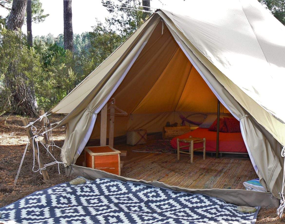 Tente safari spacieuse en pleine nature, avec un lit douillet et un tapis coloré.