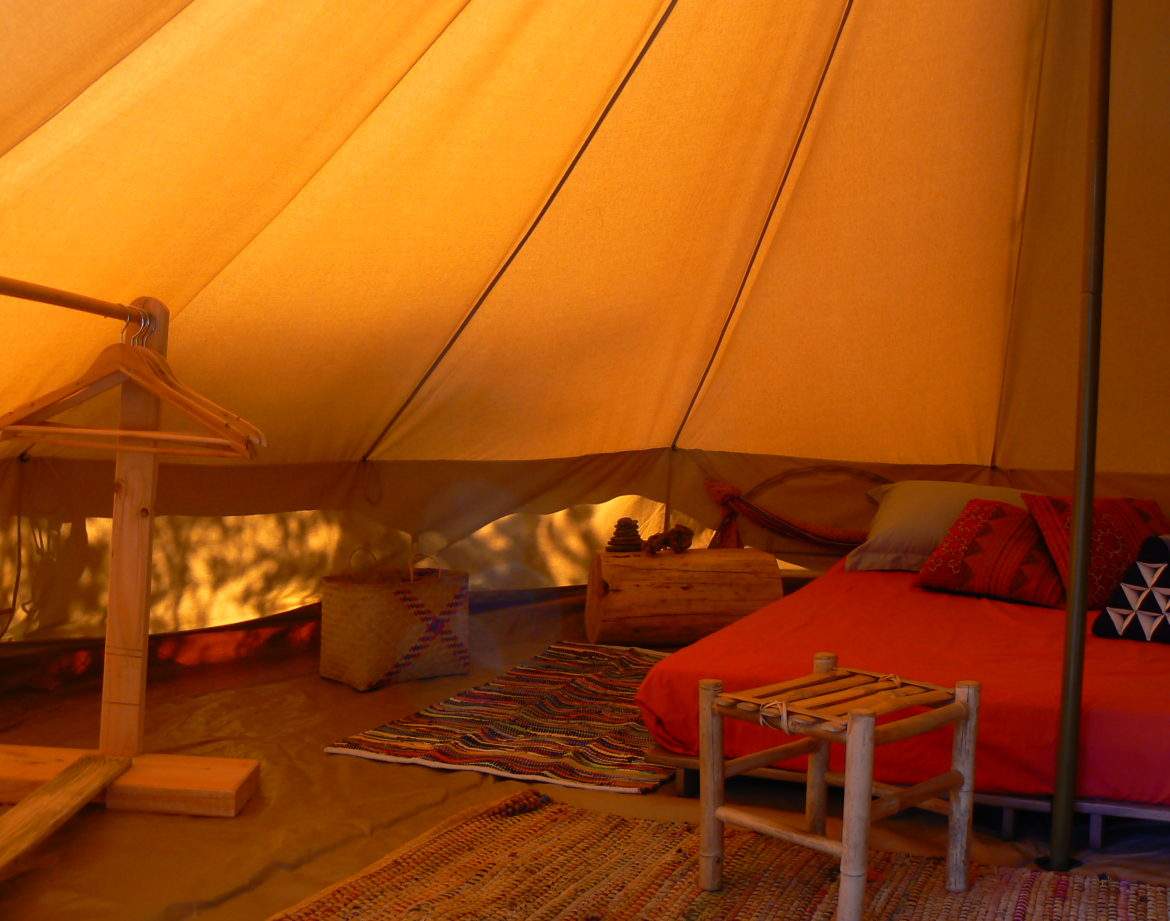 Tente safari confortable avec lit douillet et décor coloré, idéale pour un séjour insolite.