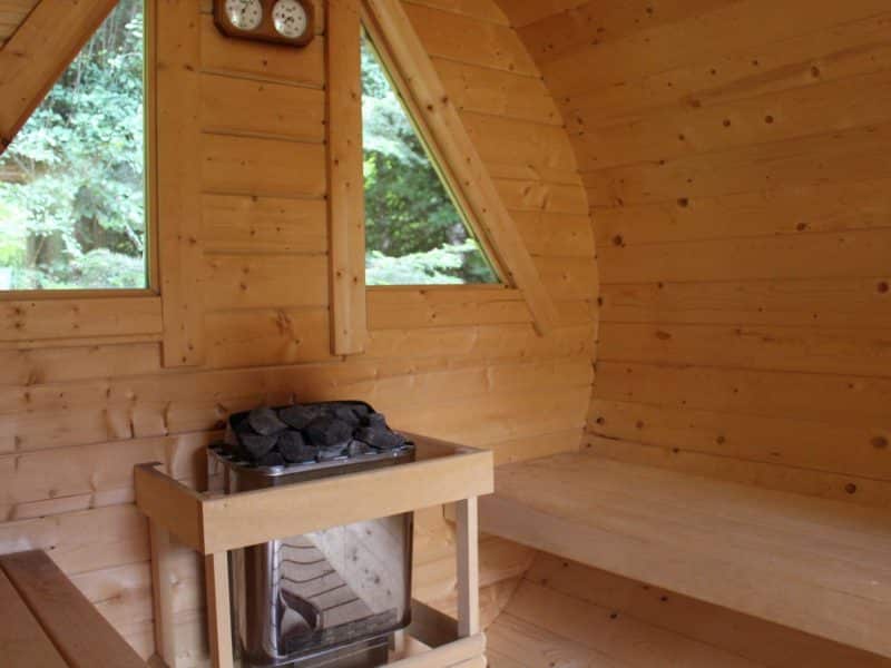 Intérieur dun sauna en bois, avec bancs et poêle à pierres. Ambiance chaleureuse et naturelle.