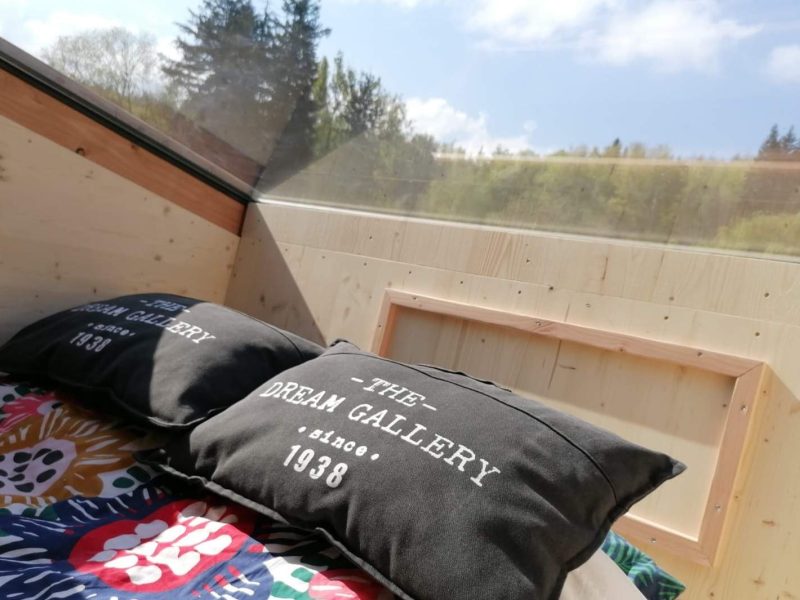 Cabane moderne avec grandes fenêtres et coussins confortables.