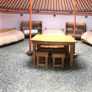 Yourte spacieuse en Auvergne-Rhône-Alpes, avec lits en bois et sol en gravier.