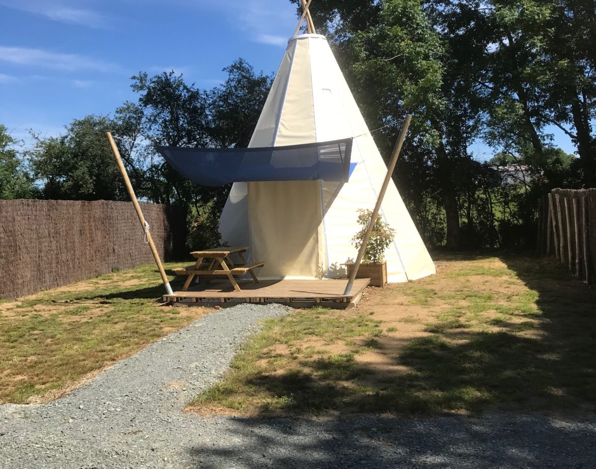 Tente tipie spacieuse avec terrasse, entourée de verdure au Pays de la Loire.