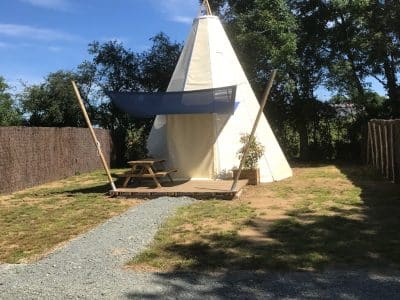 Tente tipie spacieuse avec terrasse, entourée de verdure au Pays de la Loire.