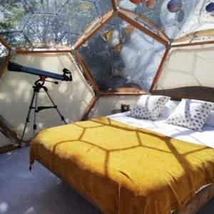 Dôme transparent en Bretagne avec lit douillet et télescope pour observer les étoiles.