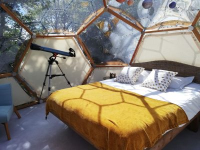 Dôme transparent en Bretagne avec lit douillet et télescope pour observer les étoiles.