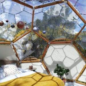Dôme transparent en Bretagne, offrant une vue sur la nature et un lit douillet.