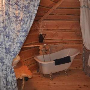 Cabane en bois avec baignoire vintage et décor floral, idéale pour un séjour romantique.