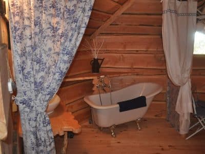 Cabane en bois avec baignoire vintage et décor floral, idéale pour un séjour romantique.