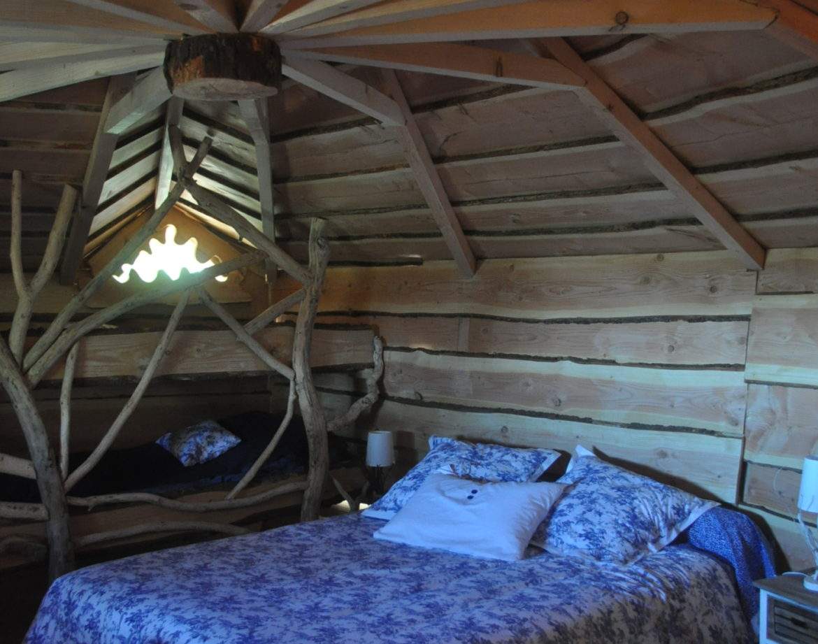 Hébergement insolite en Auvergne-Rhône-Alpes, chambre en bois avec lit douillet et décor naturel.