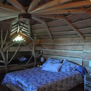 Hébergement insolite en Auvergne-Rhône-Alpes, chambre en bois avec lit douillet et décor naturel.