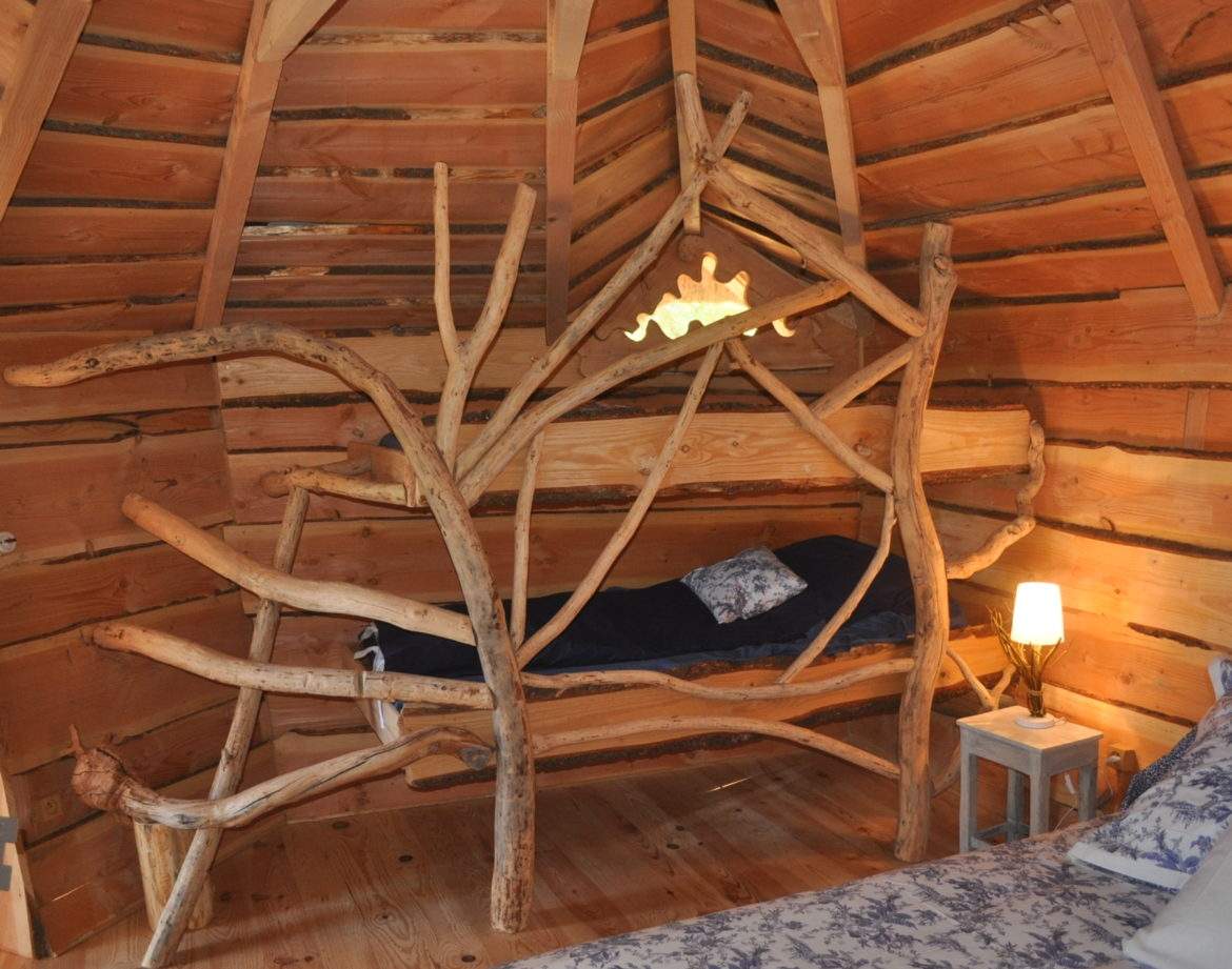Hébergement insolite en Auvergne-Rhône-Alpes avec lit en branches et ambiance boisée.