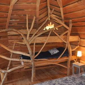 Hébergement insolite en Auvergne-Rhône-Alpes avec lit en branches et ambiance boisée.