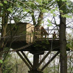 Cabane dans les arbres en Basse-Normandie, perchée entre les feuillages verdoyants.