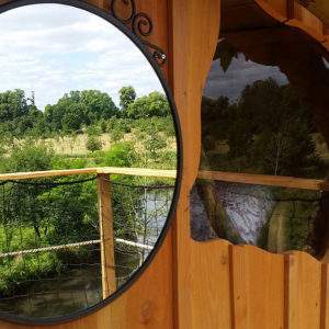 Cabane perchée en Basse-Normandie, avec vue sur la nature et un miroir rond.