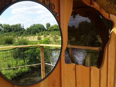 Cabane perchée en Basse-Normandie, avec vue sur la nature et un miroir rond.