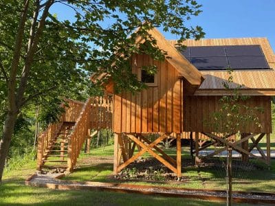 Cabane en bois sur pilotis, avec panneaux solaires, entourée de verdure en Provence.