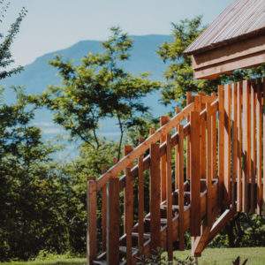 Cabane en bois perchée, avec un escalier en bois et vue sur les montagnes.