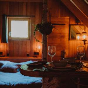 Chalet en bois chaleureux avec lit douillet et table élégante pour un séjour romantique.