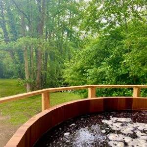 Hébergement insolite en Pays de la Loire avec un jacuzzi en bois entouré de verdure.