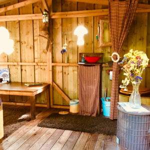 Cabane en bois à Basse-Normandie, décor chaleureux avec fleurs séchées et poêle.