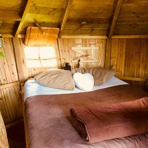 Cabane en bois cosy en Basse-Normandie, lit douillet et décoration chaleureuse.
