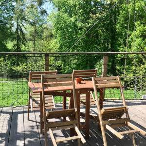 Cabane perchée en Basse-Normandie avec terrasse en bois et vue sur la nature verdoyante.