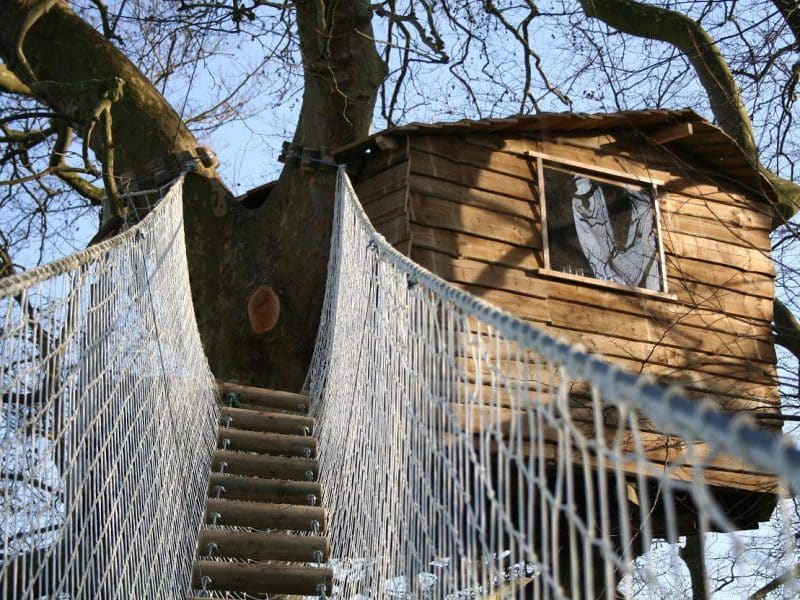 Cabane dans les arbres en Basse-Normandie, accessible par une passerelle suspendue.