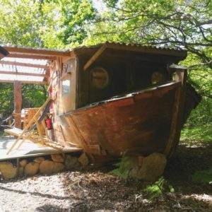 Hébergement insolite en bateau en Basse-Normandie, niché sous les arbres verdoyants.
