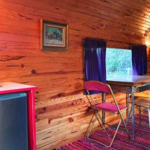Hébergement insolite en bois avec un coin repas et une vue sur la nature.