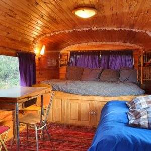 Hébergement insolite : une roulotte en bois avec lit douillet et décor chaleureux.