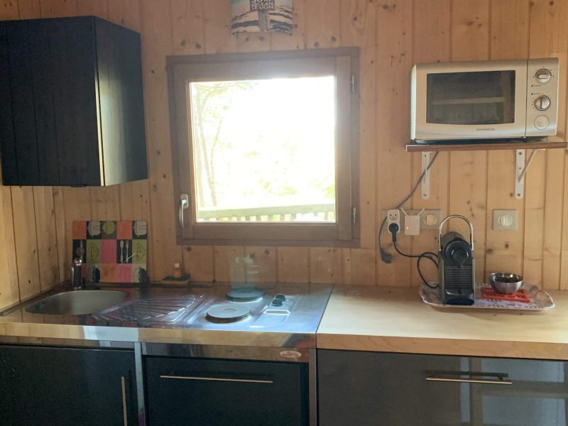 Chalet en bois avec cuisine moderne et fenêtre offrant une vue sur la nature.