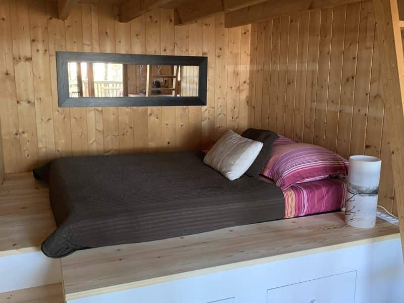 Chalet en bois avec lit douillet et décoration chaleureuse. Ambiance cosy et accueillante.