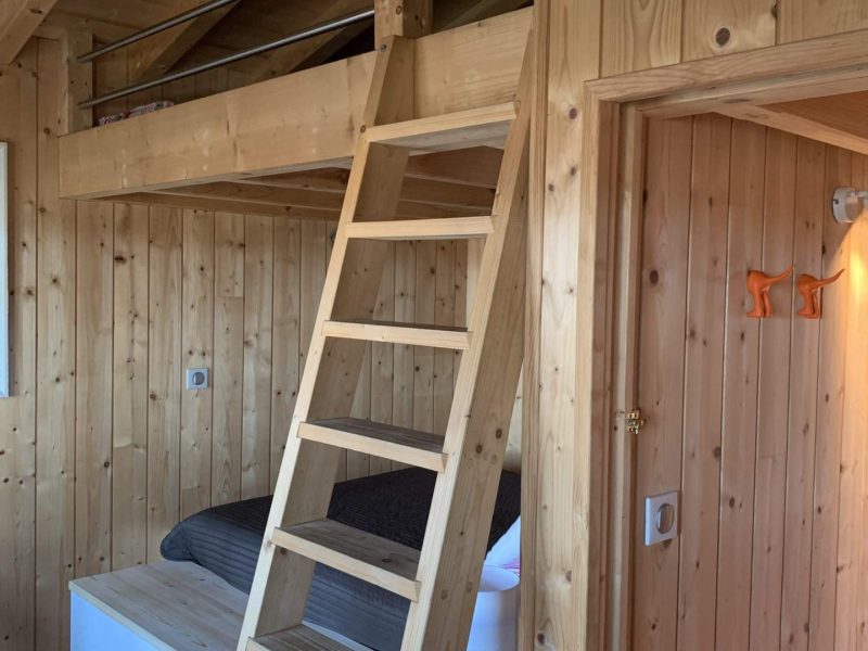 Chalet en bois avec mezzanine et échelle, ambiance chaleureuse et naturelle.