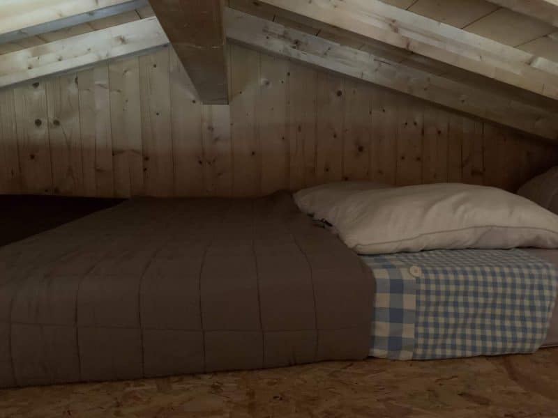 Chambre en mezzanine avec un lit douillet et des murs en bois chaleureux.