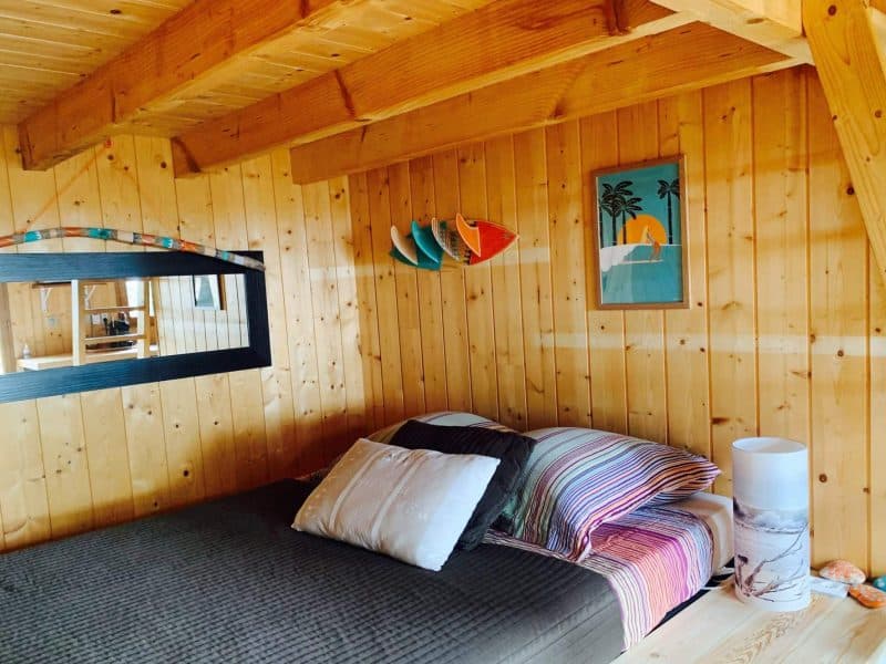Chalet en bois chaleureux avec lit douillet et décoration colorée.