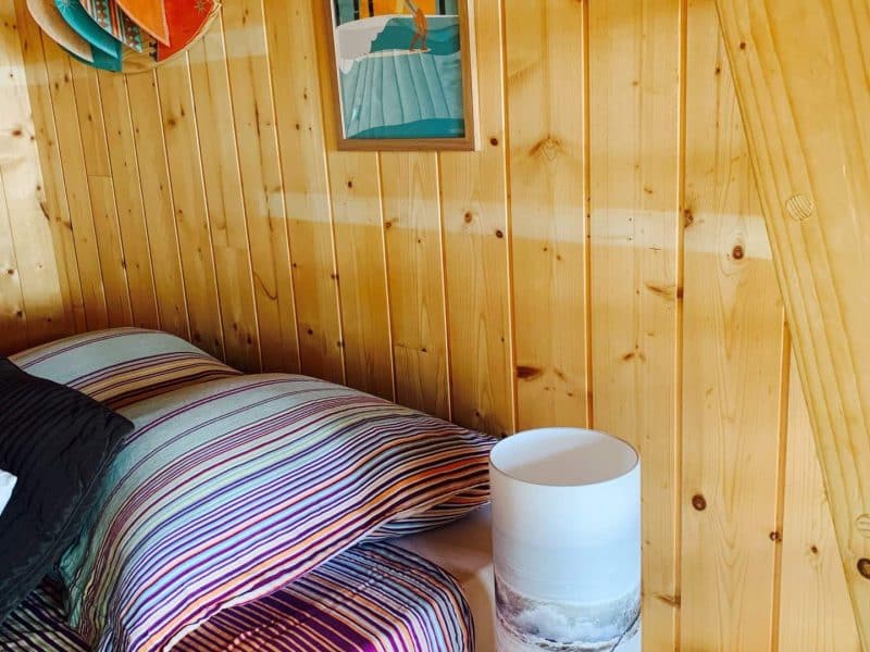 Chalet en bois chaleureux avec literie colorée et décoration artistique murale.
