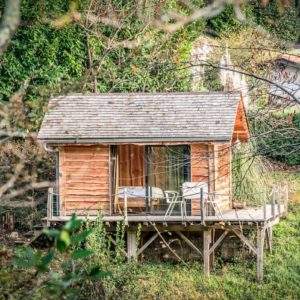Cabane en bois sur pilotis, entourée de verdure, idéale pour un séjour insolite en Aquitaine.