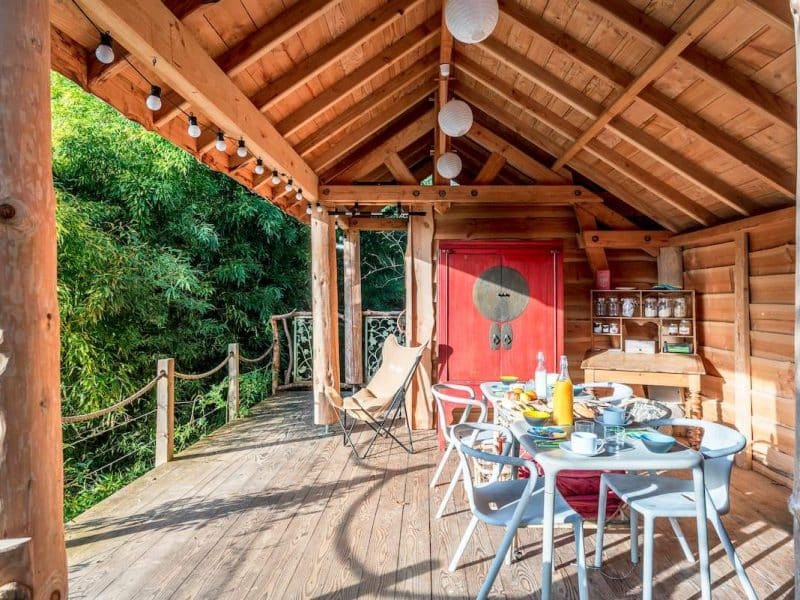Charmante cabane en bois avec terrasse, décorée pour un repas en plein air.