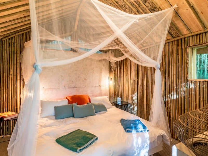 Cabane en bois avec lit douillet, drapés en tulle et décoration naturelle.
